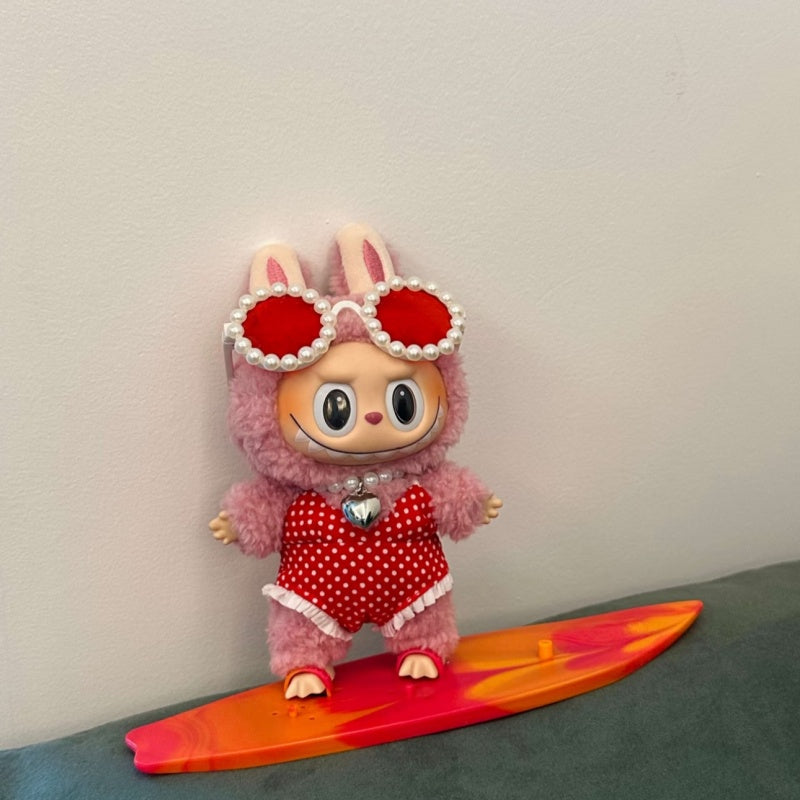 Labubu doll in red surfing outfit with heart-shaped sunglasses and orange-red surfboard. Surfing outfit fits all Labubu dolls.