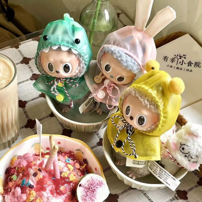 Colorful Labubu Doll Raincoats in green, pink, and yellow styled on dolls in bowls. Raincoat for Monster accessory, dolls sold separately.